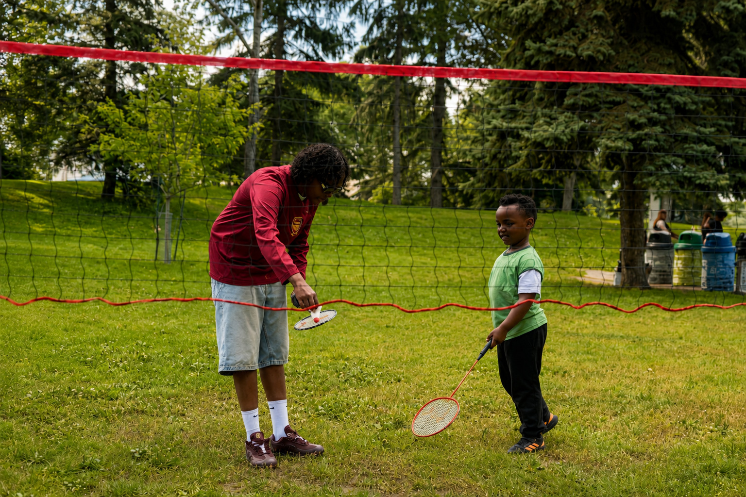 A GDS youth mentor helping a child learn badminton at a community event